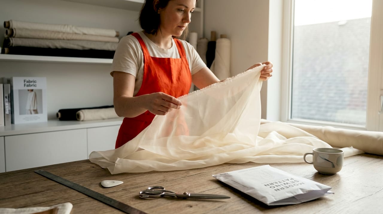 Designer checks billowing organza fabric in studio