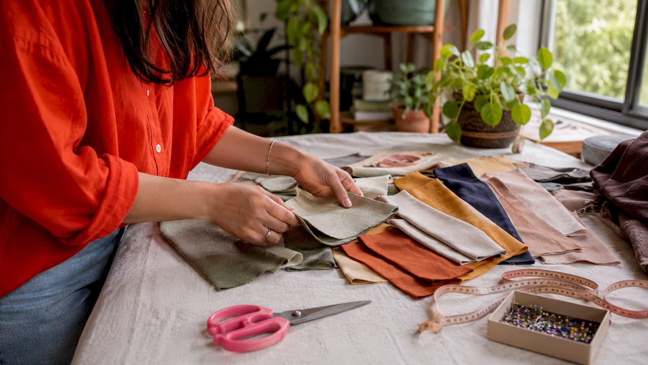 Close-up of hands with cotton fabric swatches and tools