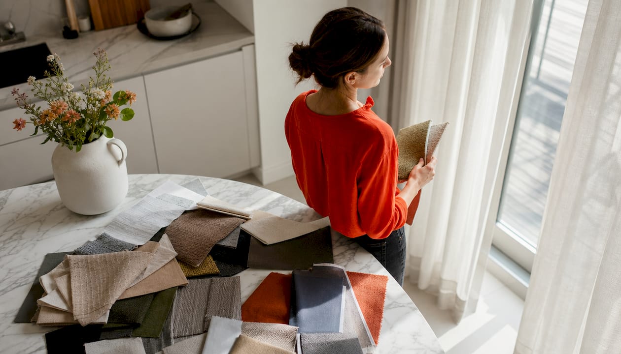 Woman examining fabric swatches by living room window