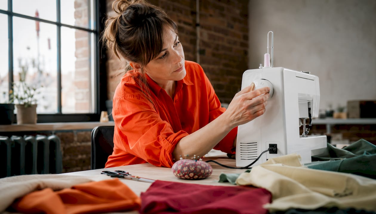 Woman adjusting sewing machine fabric tension dial