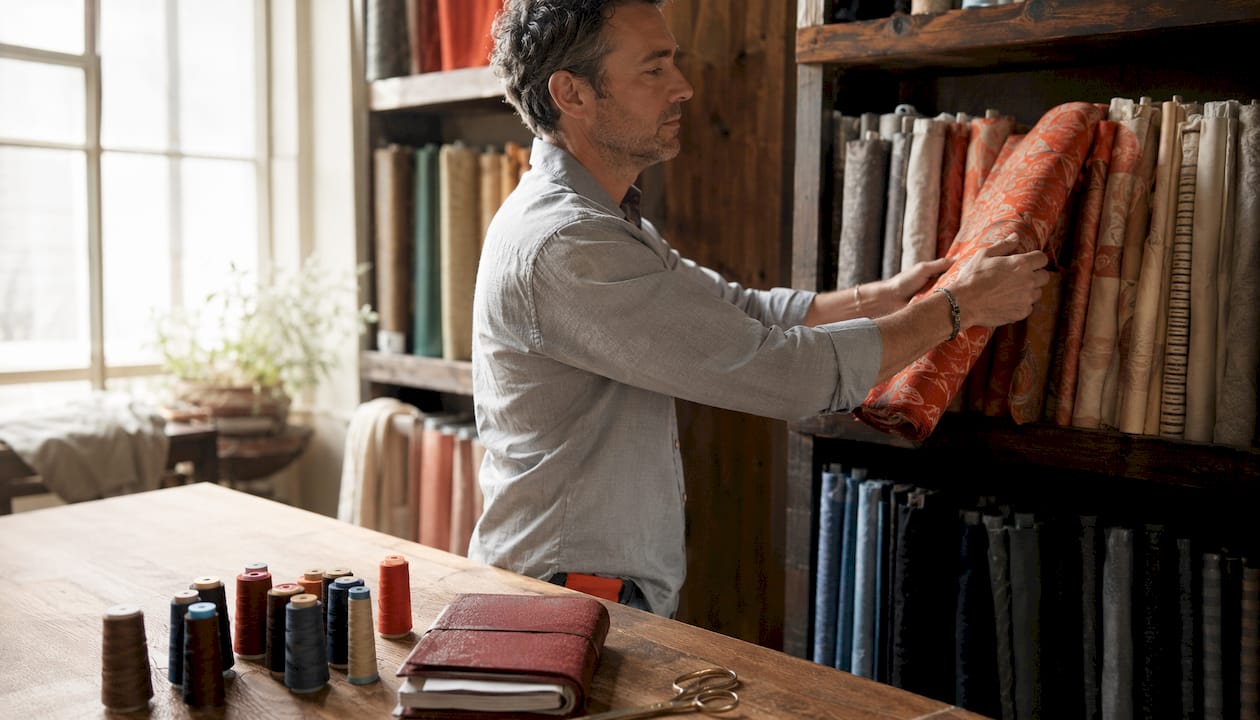 Man storing fabric bolts on shelves