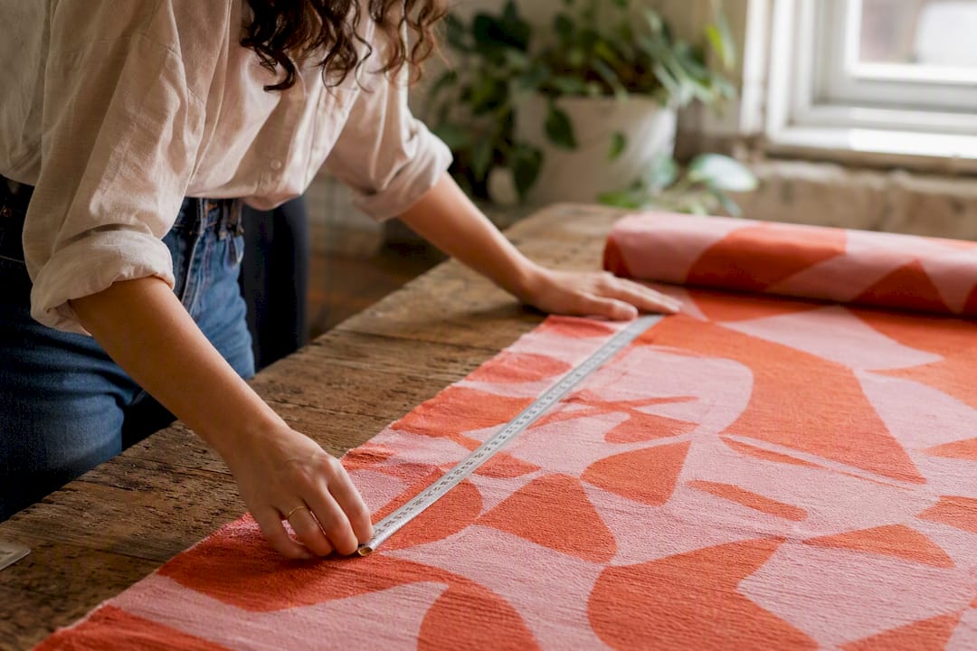 Hands measuring fabric yardage with tape measure
