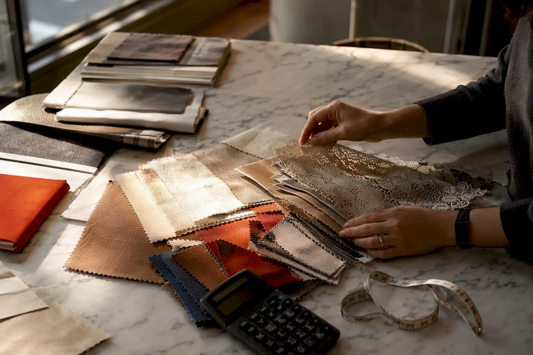 Designer arranging fabric swatches with calculator