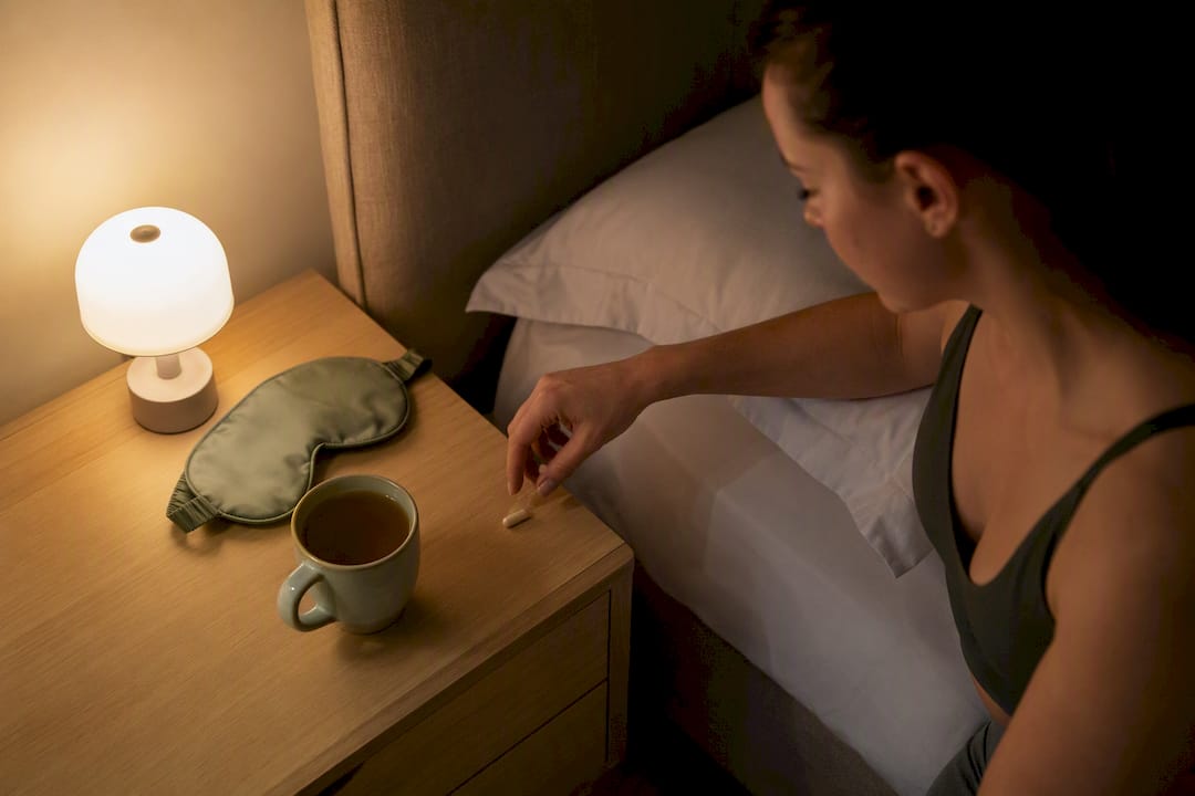 Hand taking supplement capsule by bedside
