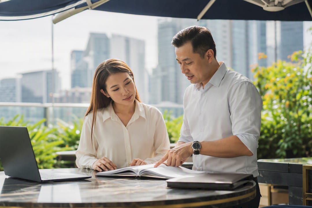 Mentor guiding a new real estate agent with manual