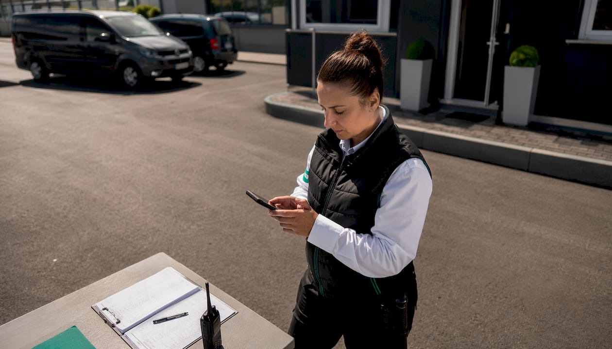 Ein Sicherheitsmitarbeiter nutzt unterwegs eine App auf dem Smartphone.