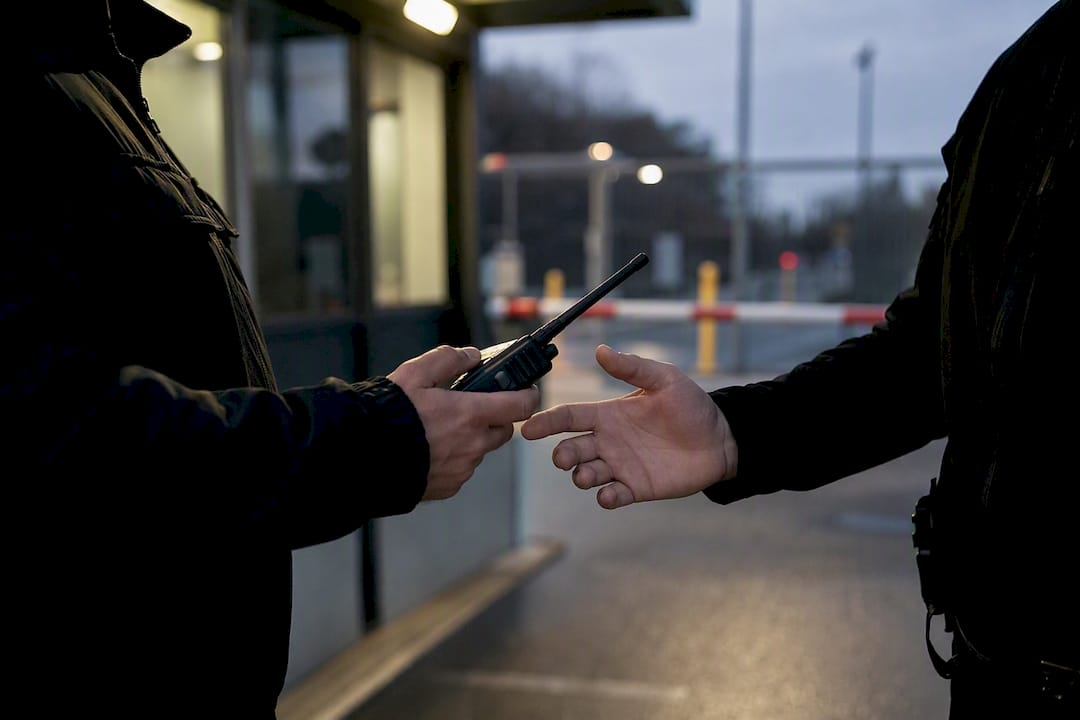 Hände tauschen Funkgerät an Sicherheitskontrolle aus