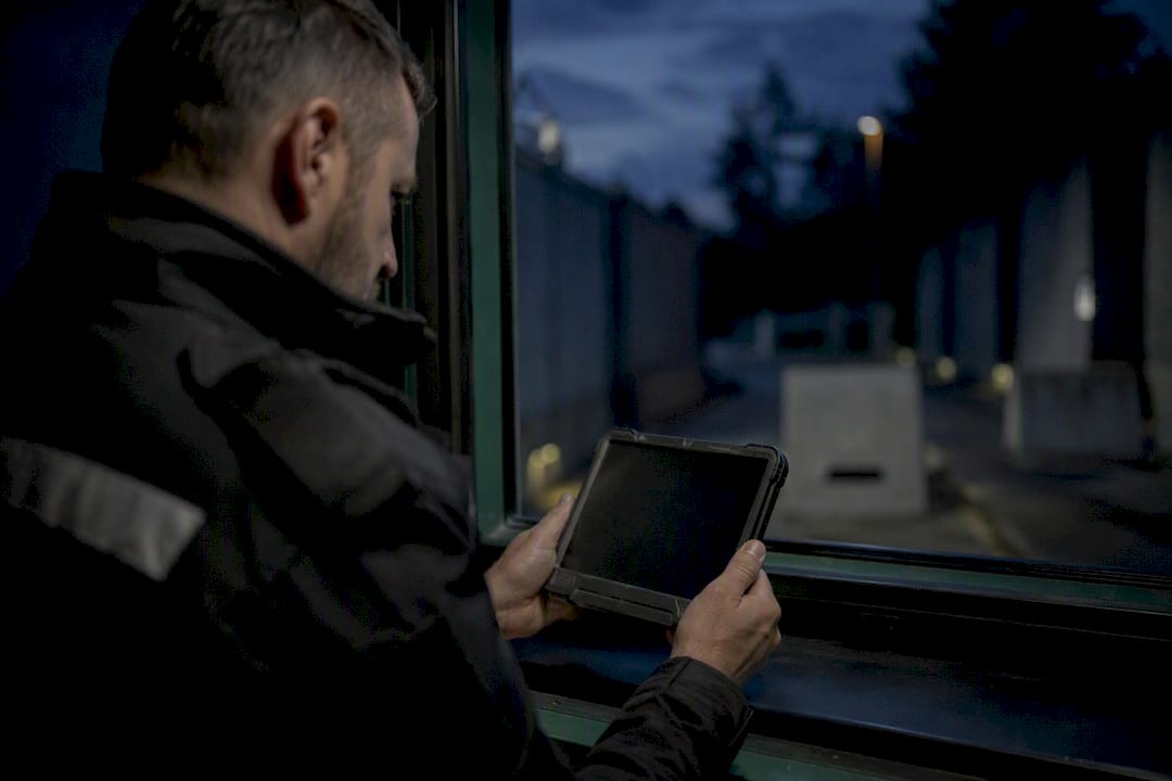 Hände, die einen Ereignisalarm an einem mobilen Sicherheitsgerät auslösen