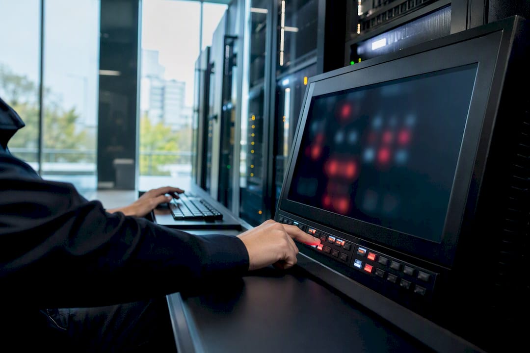 Hände, die eine Warnung an einer Netzwerküberwachungskonsole bestätigen