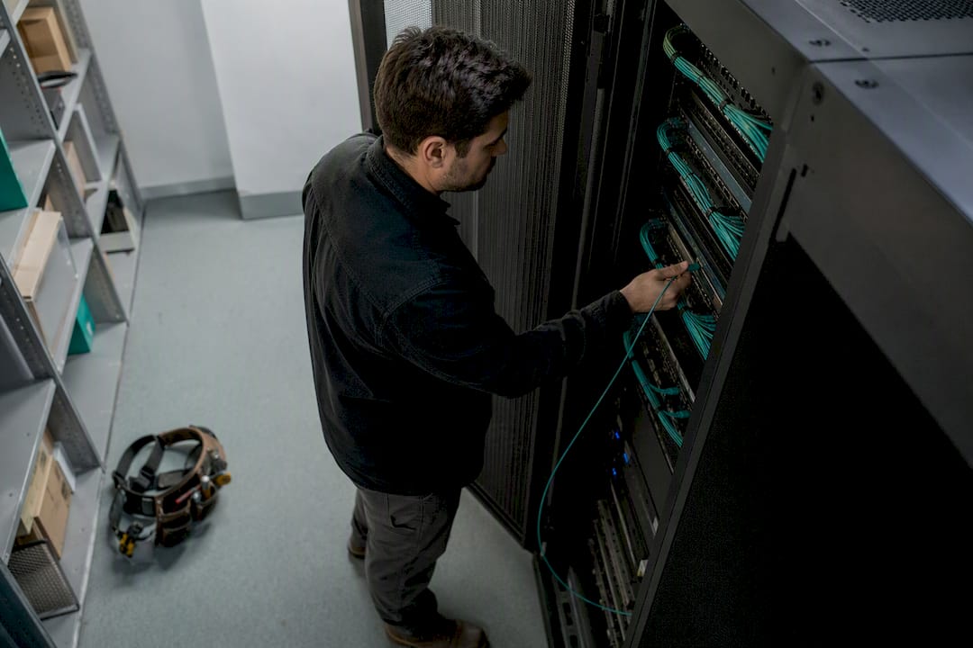 Hände verbinden ein Netzwerkkabel im Serverraum