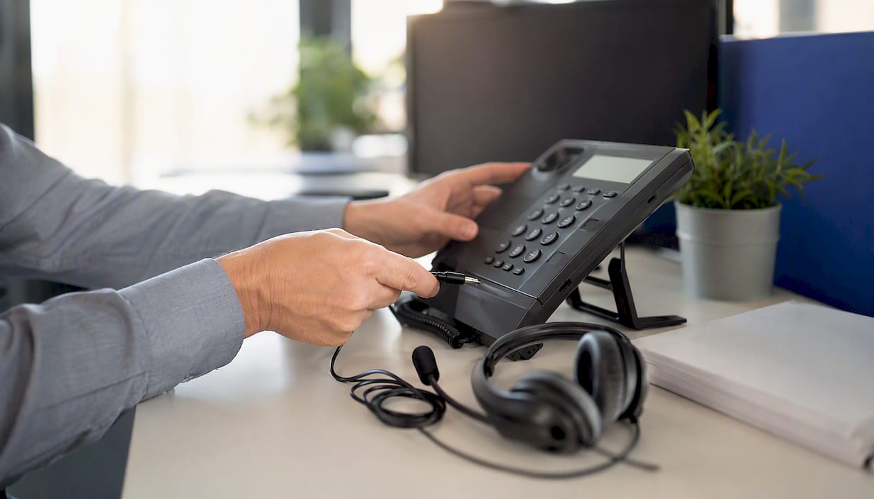 Hands connecting headset cable to phone