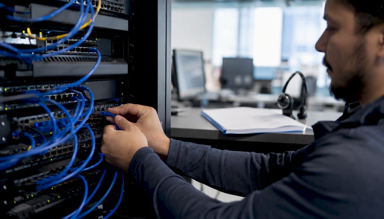 Hands setting up network cables on server rack