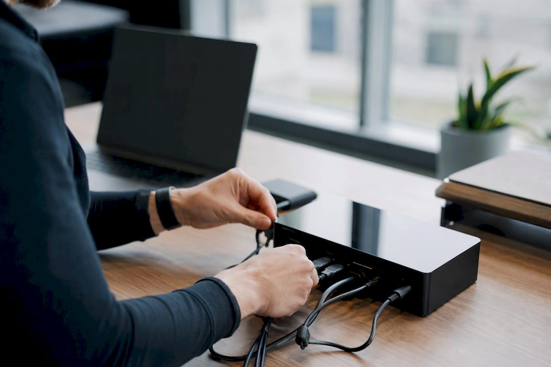 Hands adjusting cables on black tech device