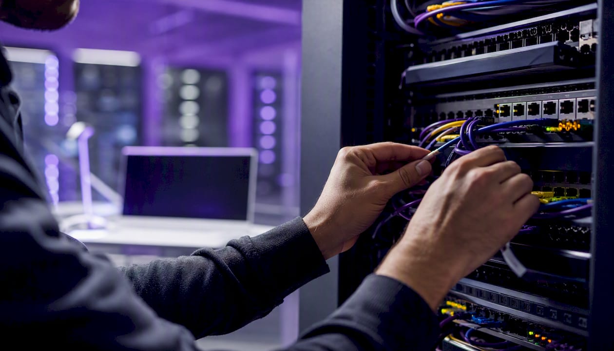 Hands connecting network cables in server room