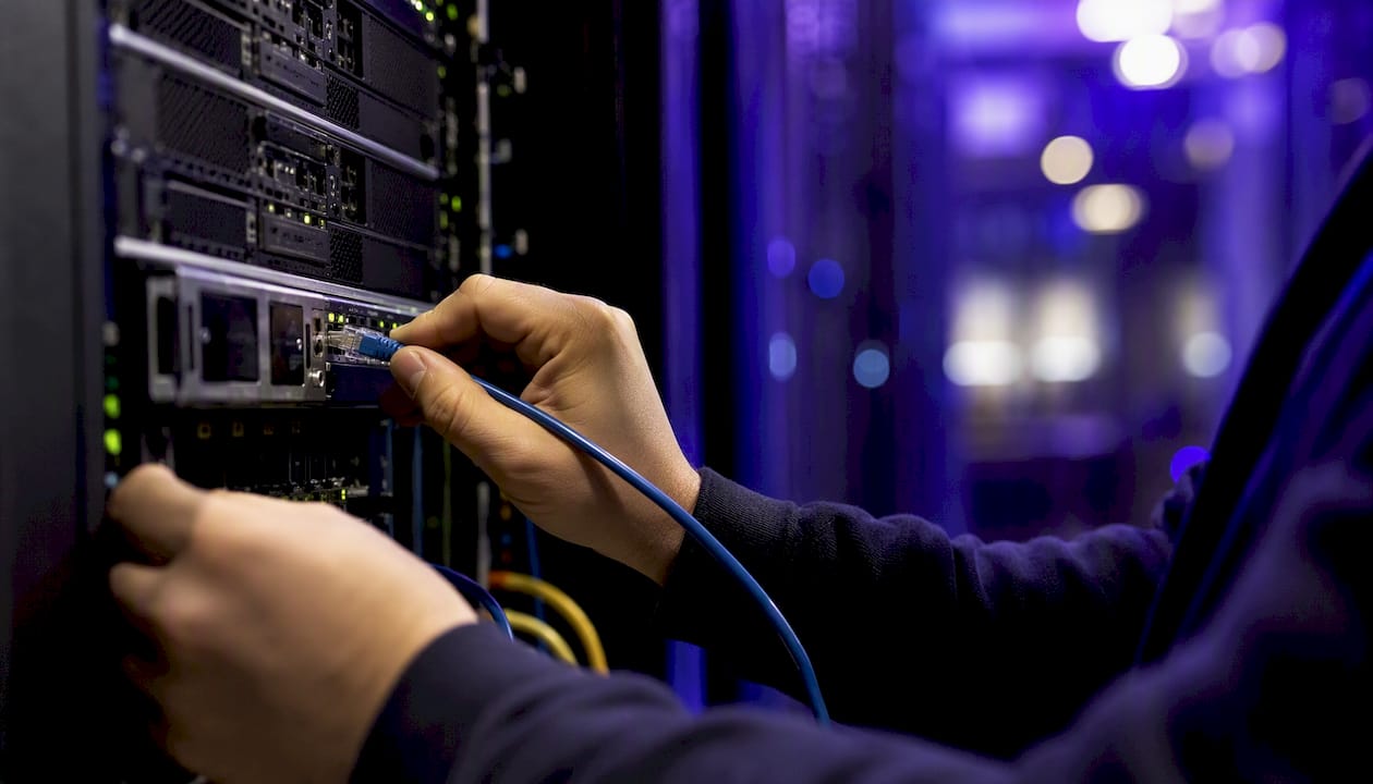 Hands connecting network cable in data center aisle