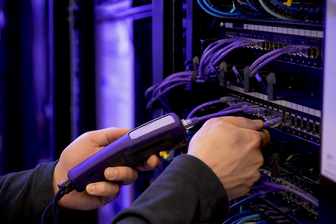 Hands testing network cable in data center