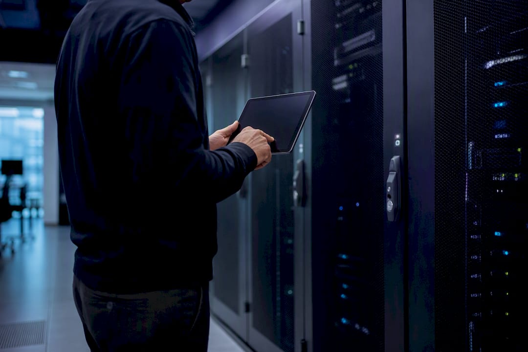 Hands holding tablet near secured server racks