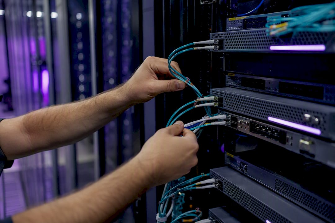 Hands connecting cables in secure server rack