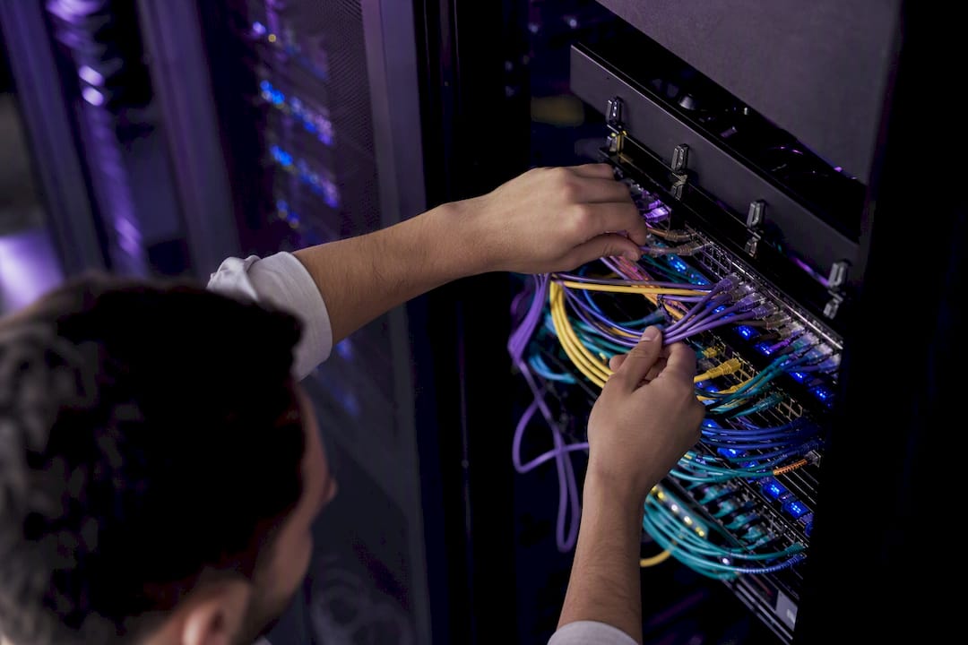 Hands connecting cables to database patch panel