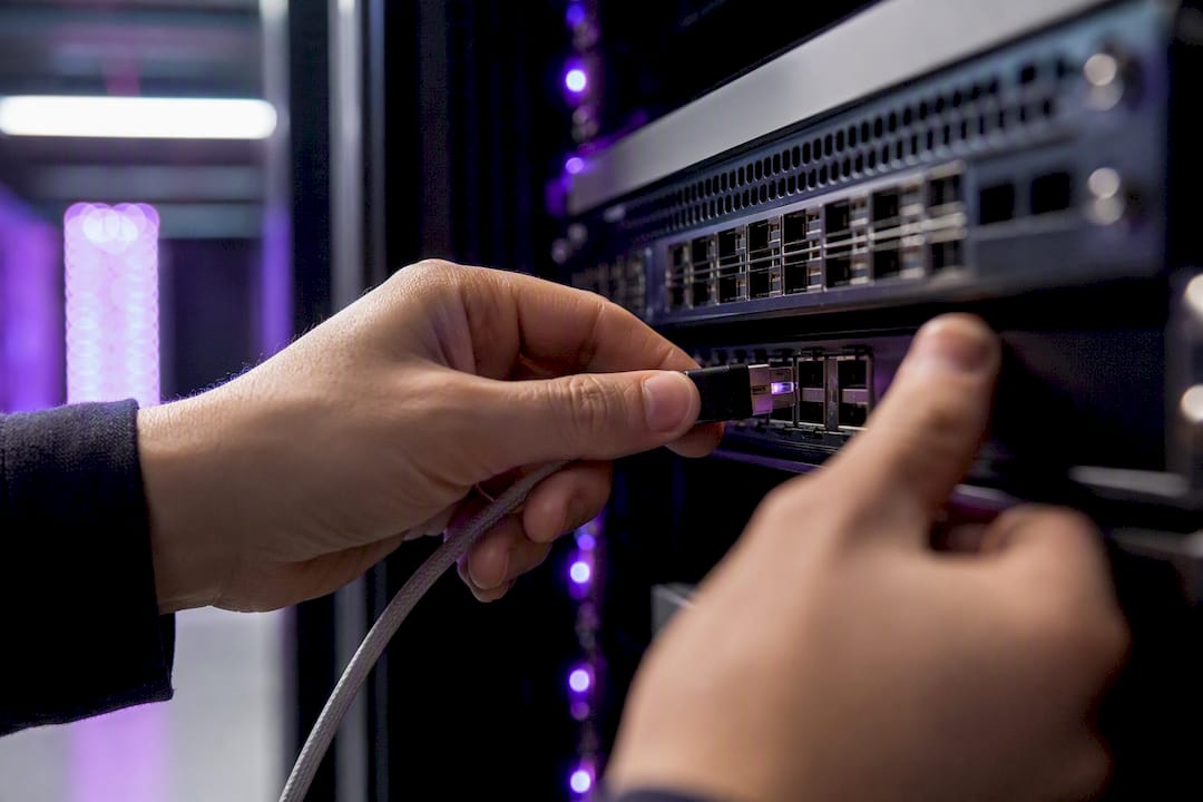 Hands connecting network cable in data center