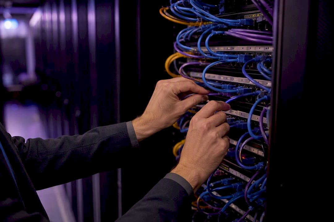 Hands connecting network cable in data center