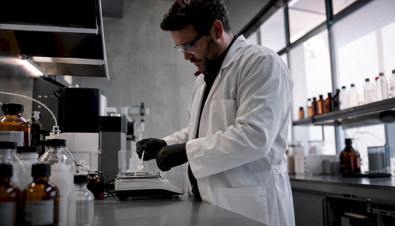 Chemist weighing 7-hydroxymitragynine powder in lab