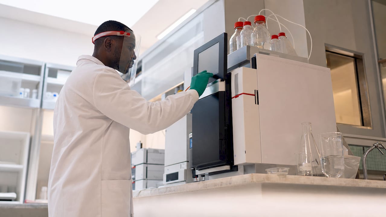 Technician operating chromatography equipment in lab