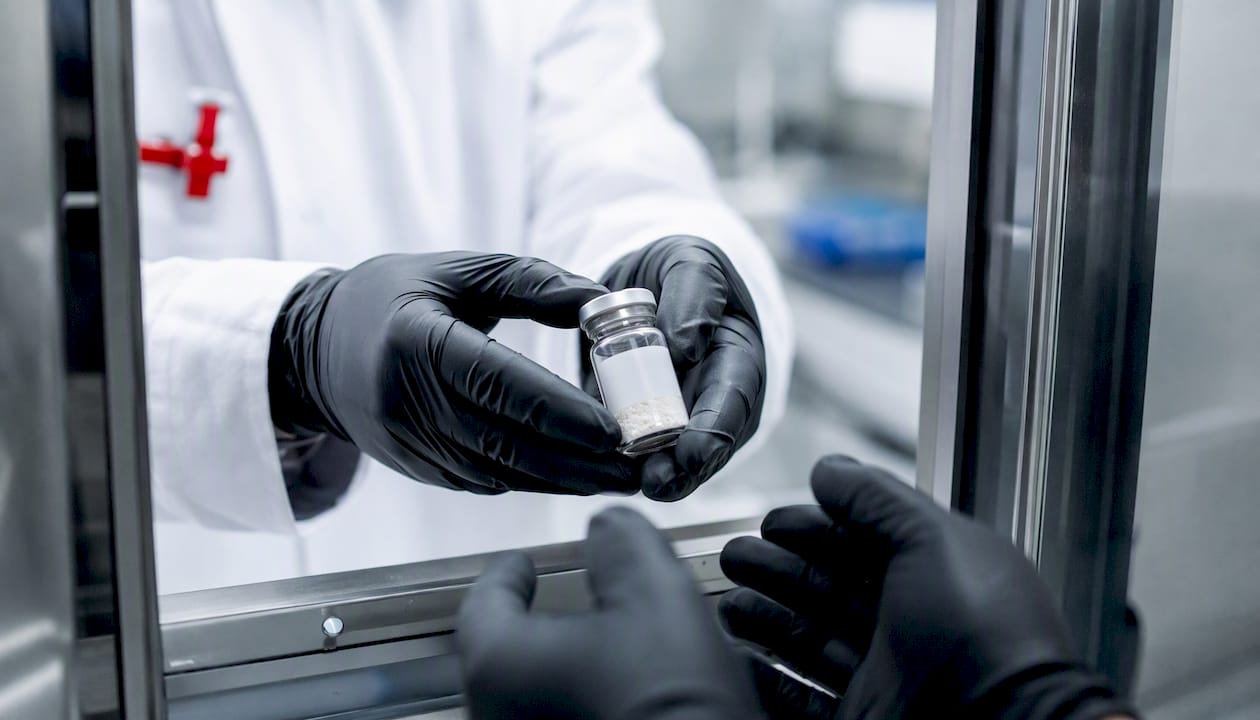 Hands transferring sealed lab vial