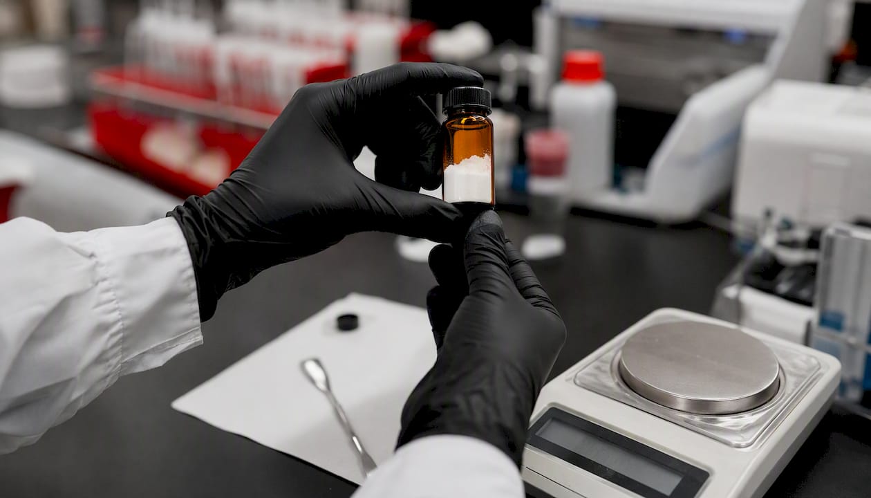 Hands inspecting research chemical vial close-up