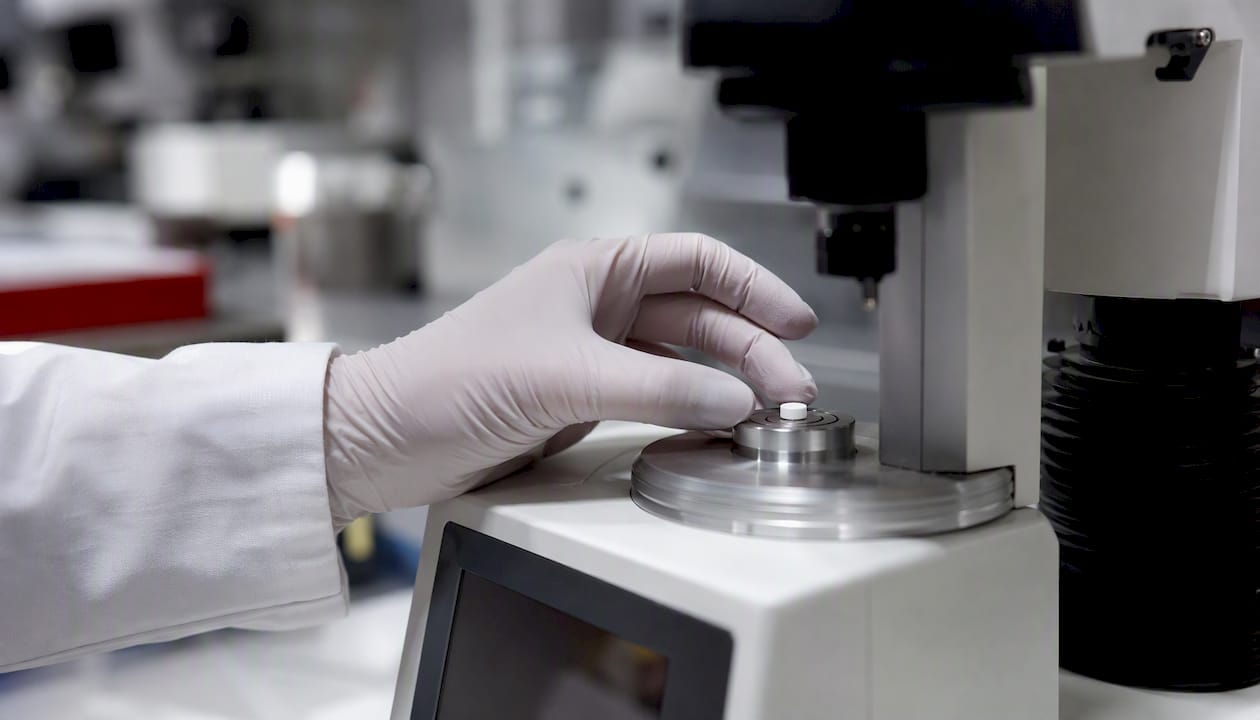 Hand placing research tablet on hardness tester