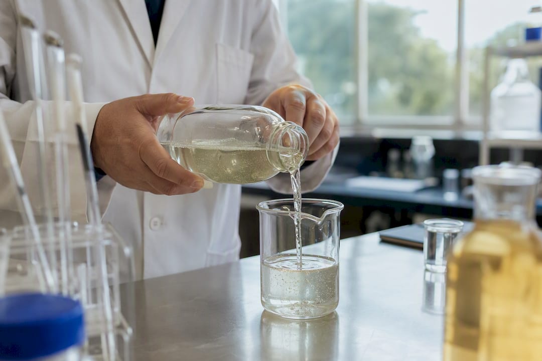 Hands pouring surfactant solution in lab