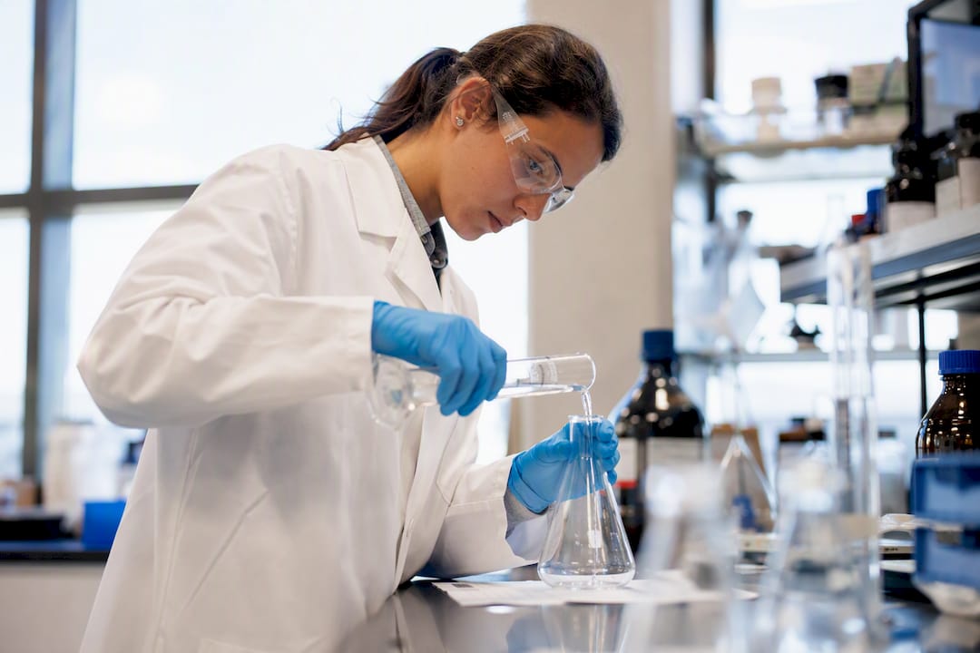 Chemist pouring liquid into flask in lab