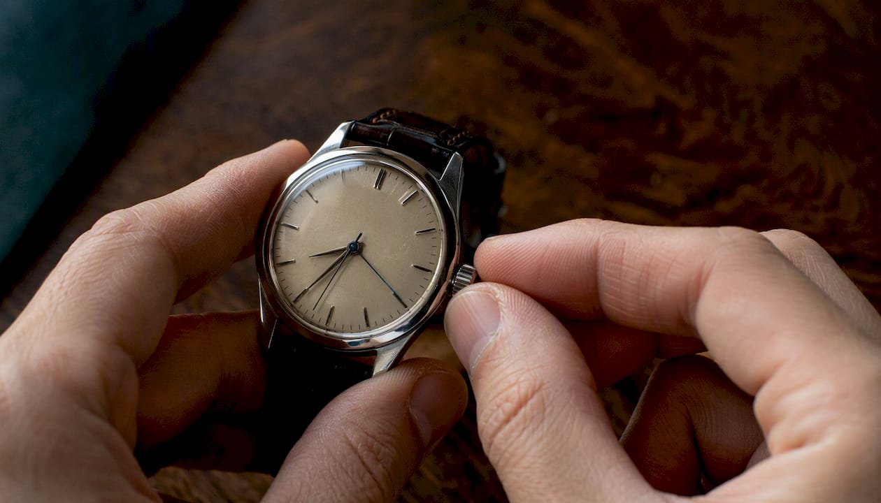Hands adjusting wristwatch dial close-up