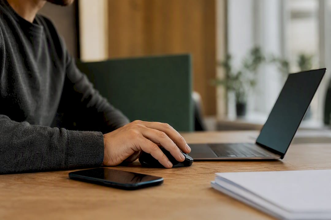 Hand on mouse near dark laptop screen