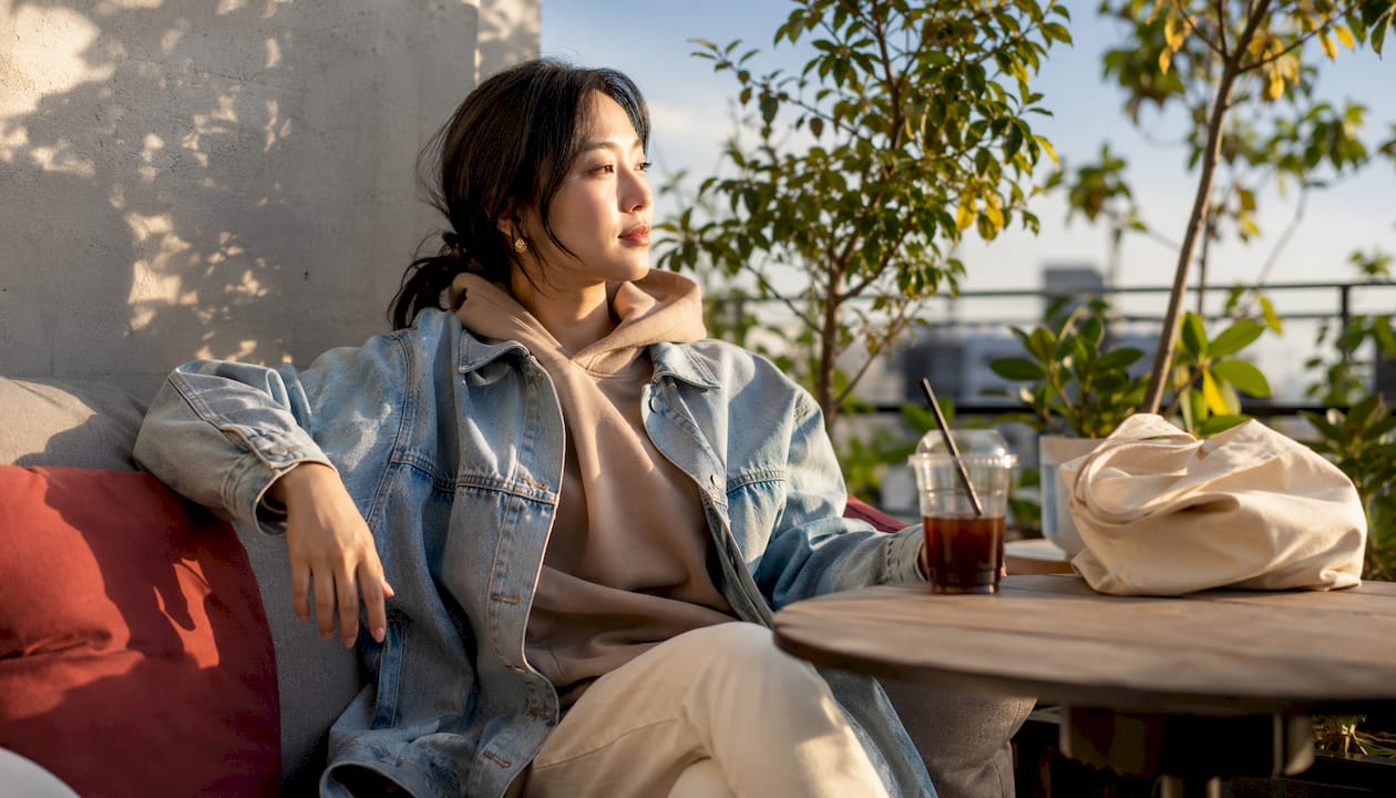 Woman wearing hoodie under denim jacket outdoors