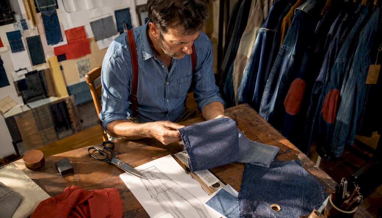 Tailor examining recycled denim fabric in studio