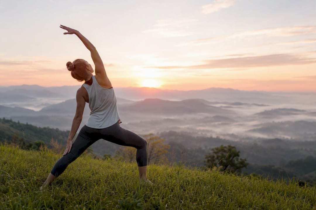 Person stretching on grass at sunrise