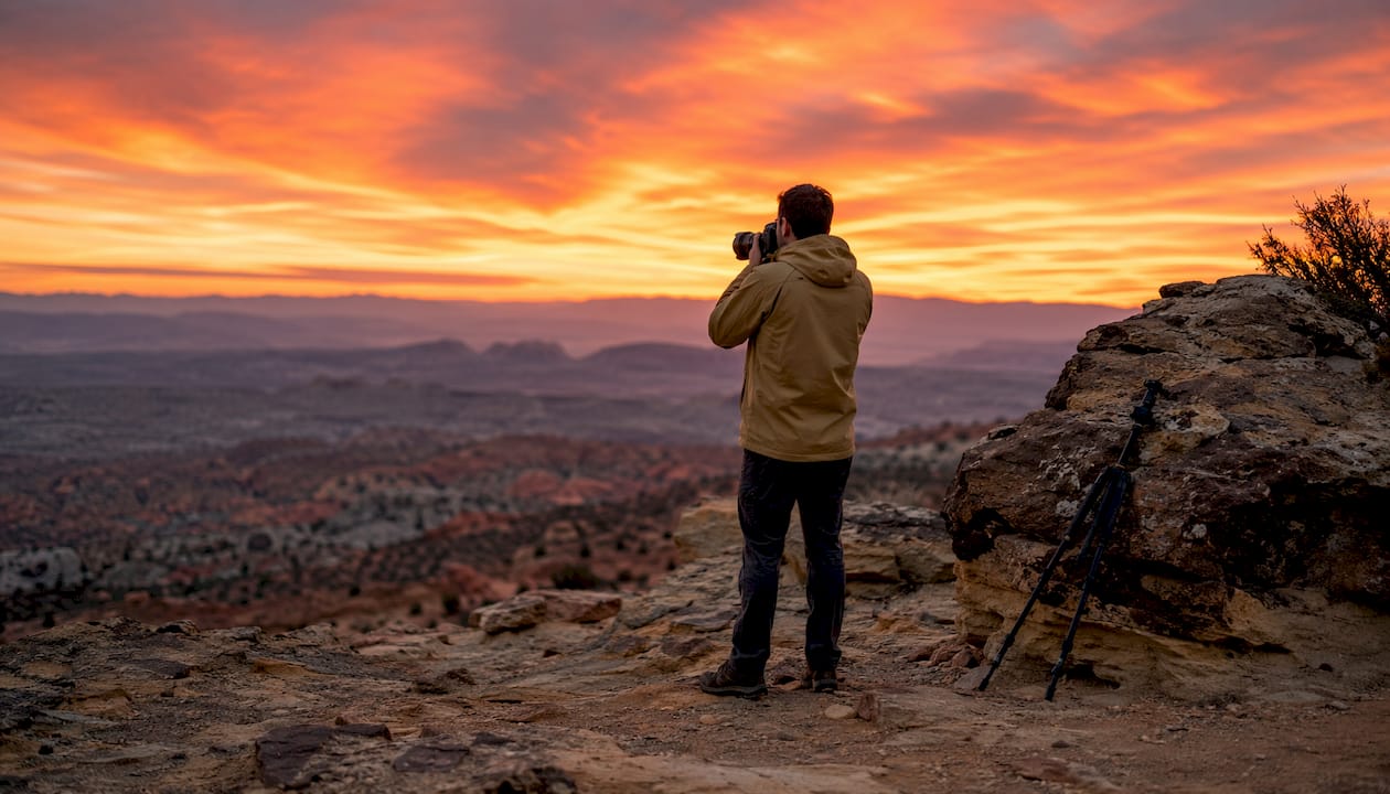 Photographer adjusting camera lens at sunset