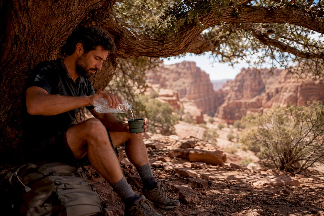 Hiker hydrating in shade to recover from heat exhaustion