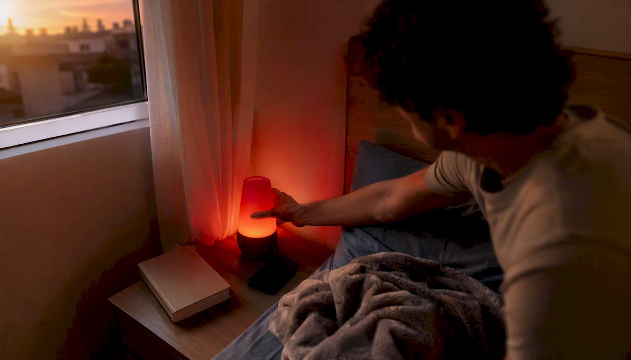 Una persona ajusta la lámpara de luz roja que tiene junto a la cama.