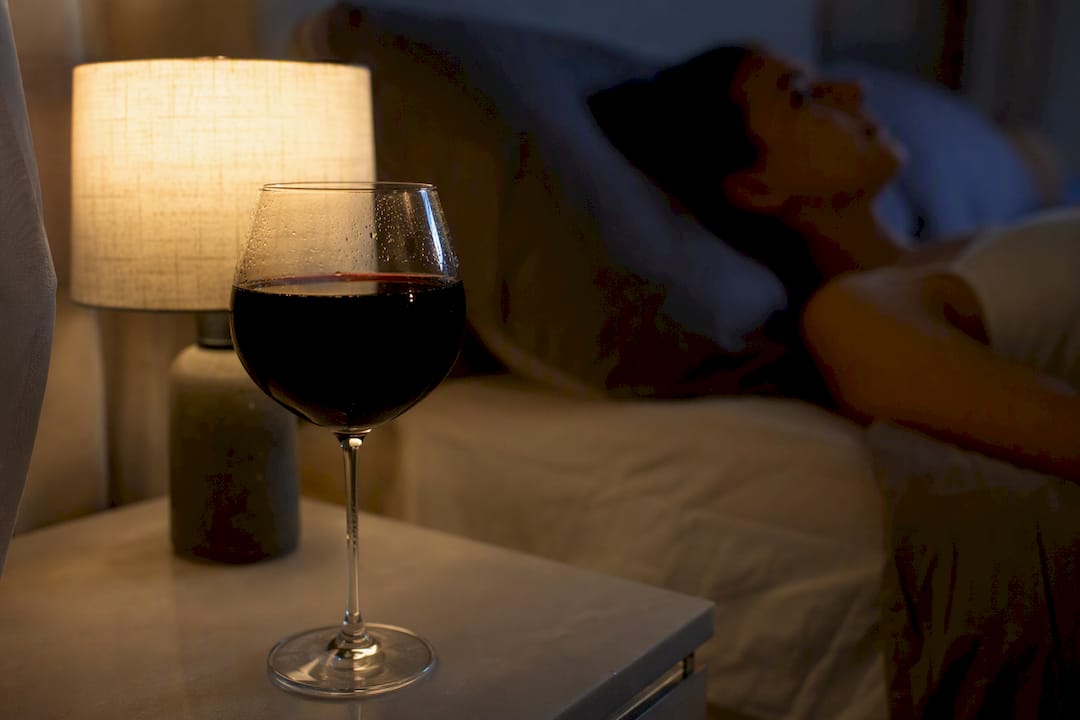Una copa de vino sobre la mesita de noche, símbolo de ese pequeño ritual de tomar una copa antes de dormir.
