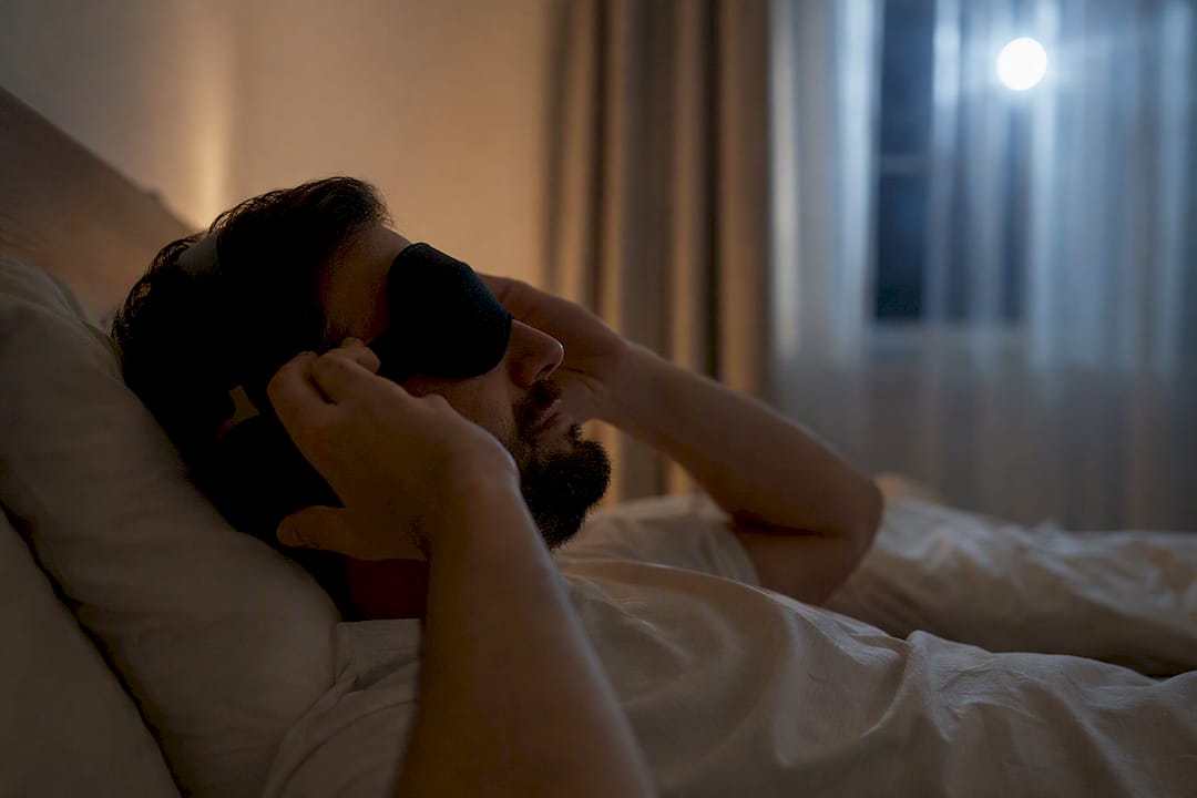 Una persona se coloca los auriculares mientras se prepara para dormir.