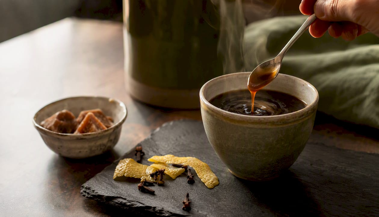 Coffee being stirred with panela syrup and spices