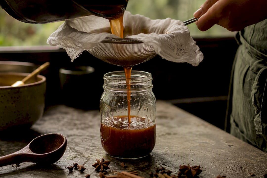 Straining panela chai syrup through cheesecloth