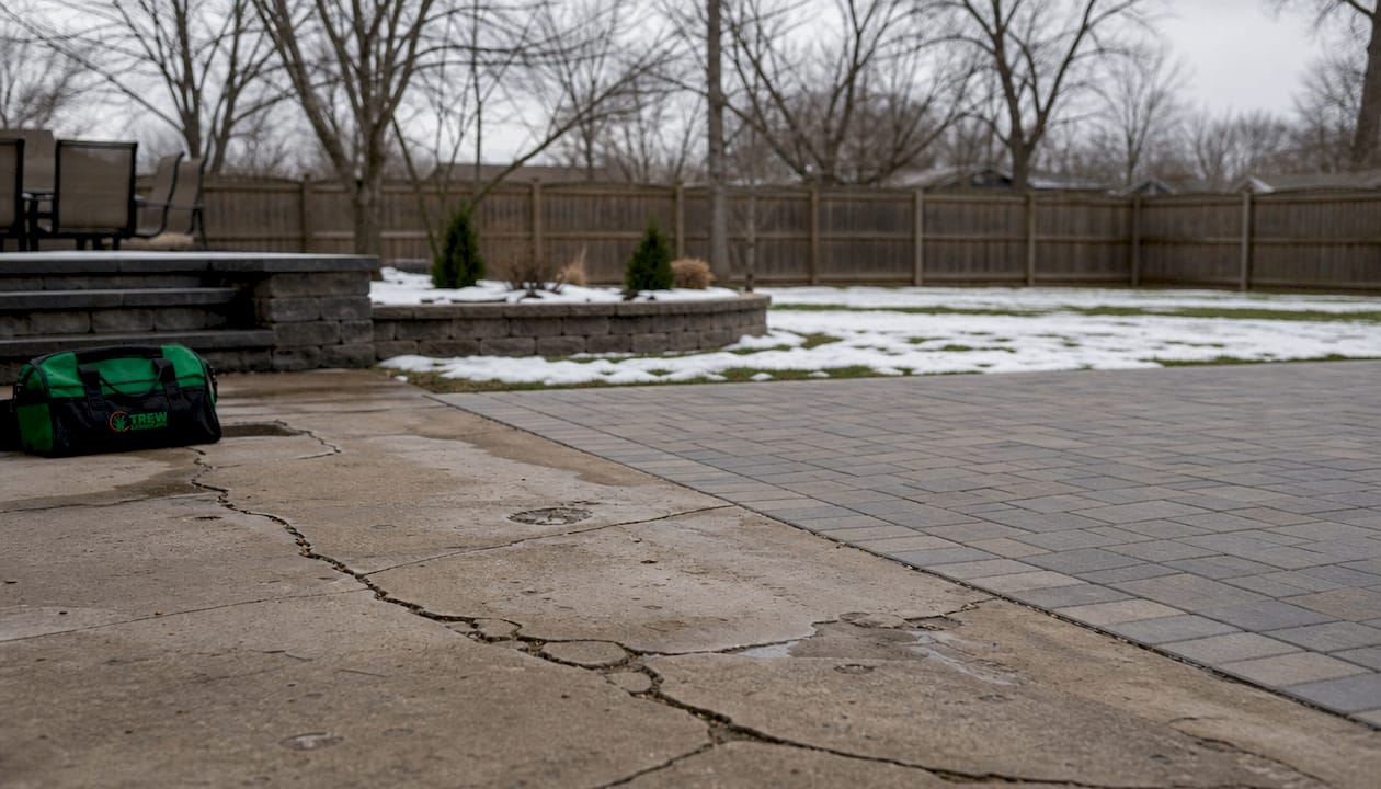 Cracked concrete and intact paver patios in winter
