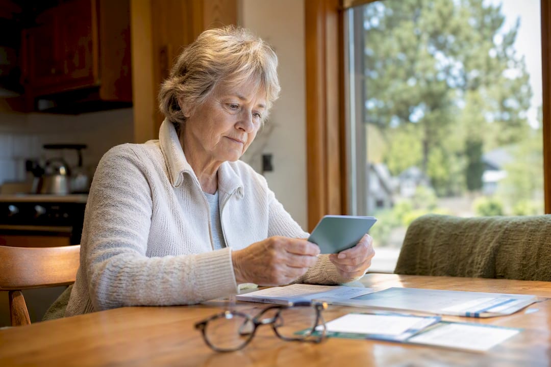 Senior woman reviewing dental insurance cards at home