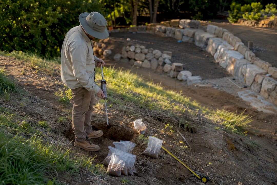 Engineer collecting soil sample near gabion site