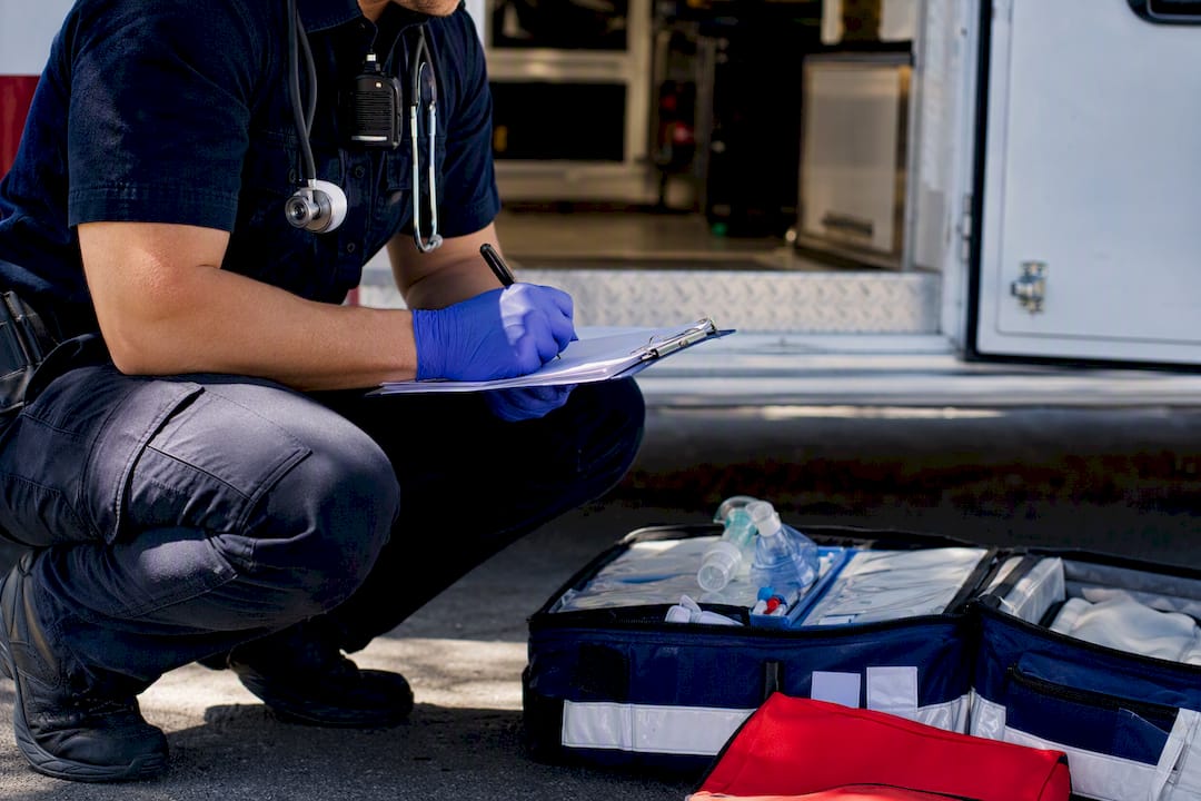 EMT writing documentation outside ambulance
