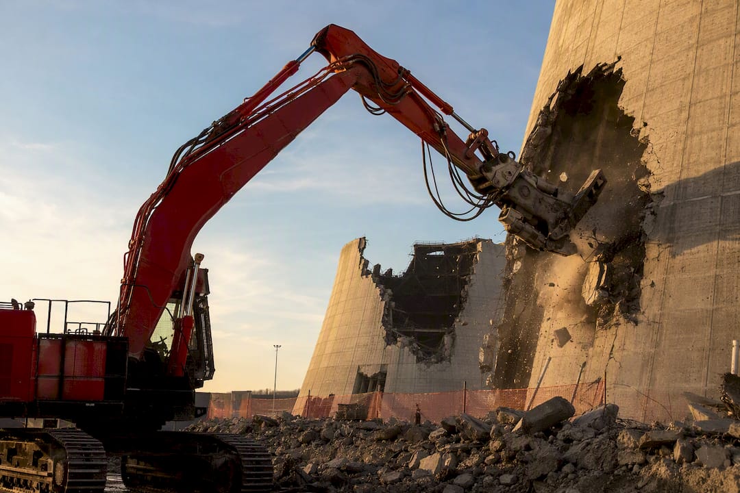 Long-reach excavator shearing cooling tower concrete