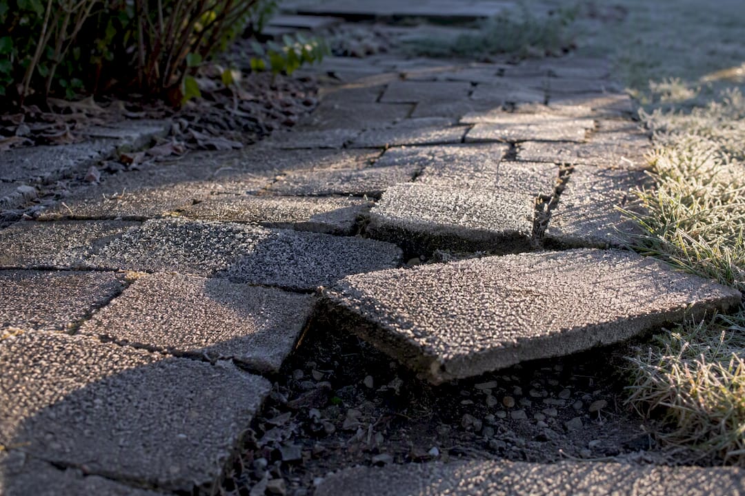 Frost heave lifts uneven stone paver walkway
